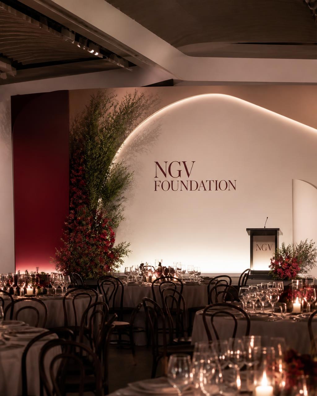 Corporate gala room with sculptural floral staging and candlelight